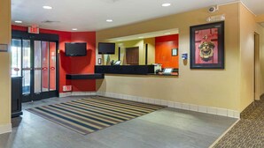 A hotel lobby with a reception desk, a large mirror, and an exit sign. - Extended Stay America Select Suites Hartford Manchester (Manchester)