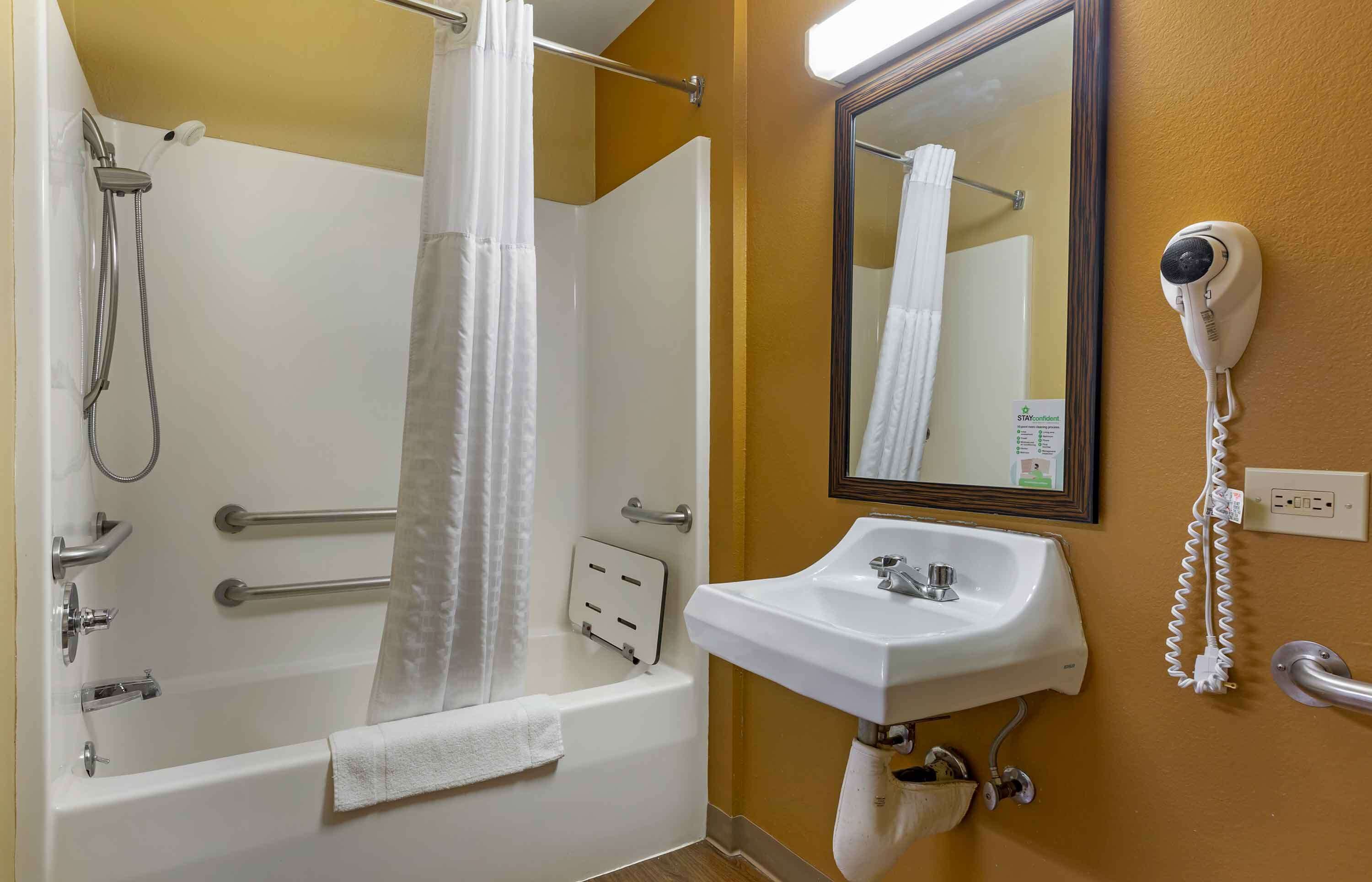 Une salle de bain équipée d’une baignoire, d’une douche, d’un lavabo, d’un sèche-cheveux et d’un miroir.
