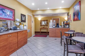A hotel room with a kitchenette, a dining area with chairs and a table, a coffee machine, and a painting on the wall. - Econo Lodge Louisville Airport (Louisville)