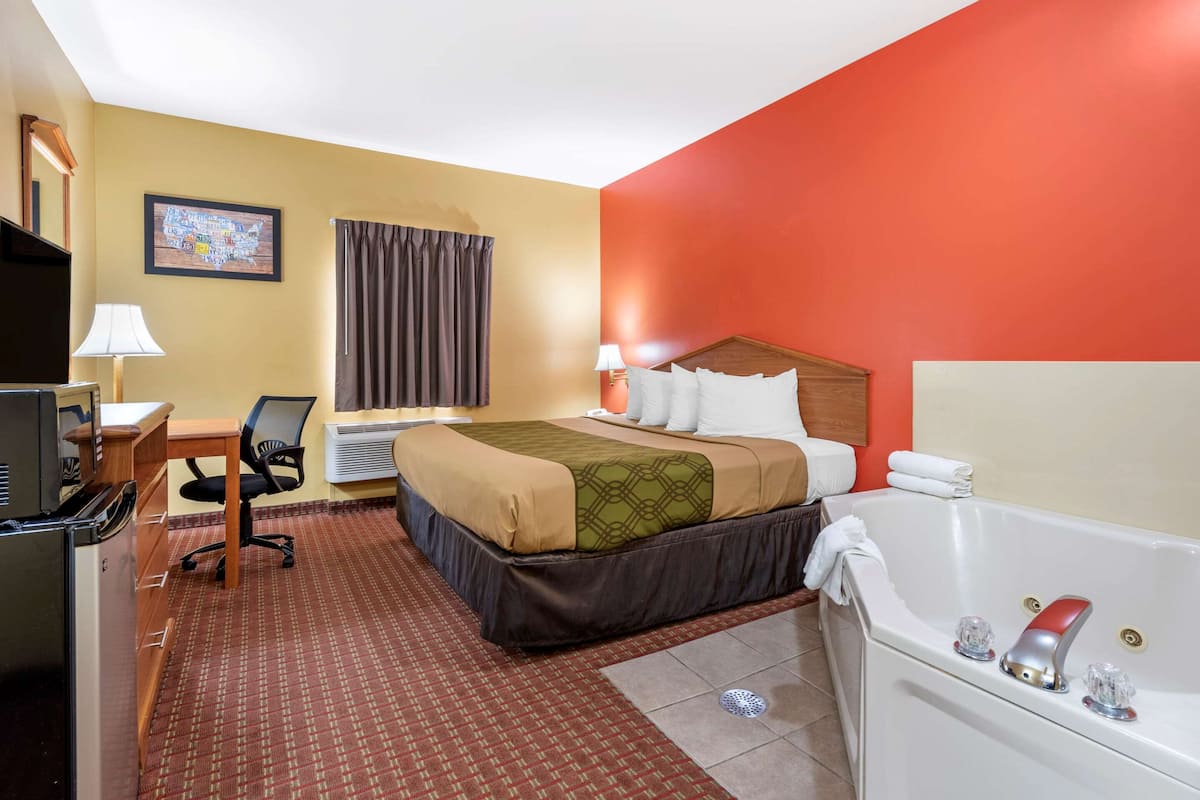 Een hotelkamer met een bed, bureau, stoel, televisie en een bad.