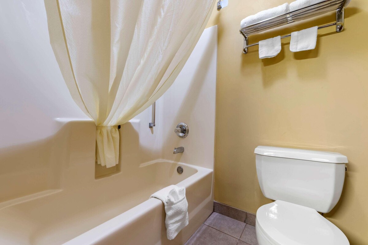 Een badkamer met een bad, toilet en handdoekrek.