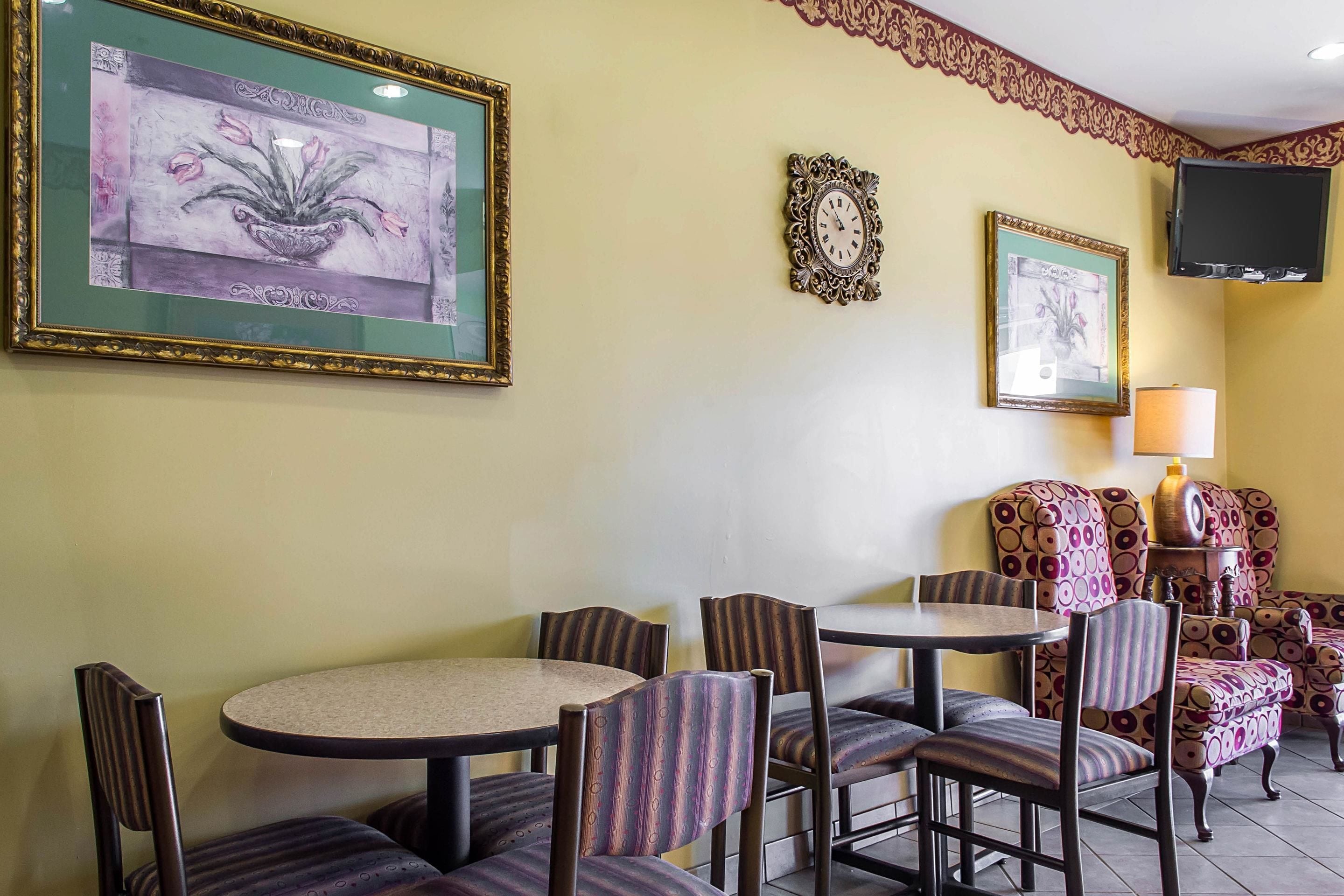 Un coin repas avec une table ronde et des chaises, un téléviseur fixé au mur et des œuvres d’art encadrées qui décorent les murs.