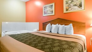 Een hotelkamer met een bed, een houten hoofdbord, twee ingekaderde foto's aan de muur en een bad.