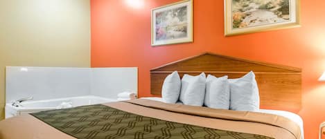 Habitación de hotel con cama, cabecero de madera, dos cuadros en la pared y una bañera.