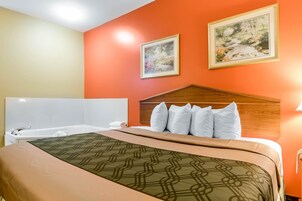 Habitación de hotel con cama, cabecero de madera, dos cuadros en la pared y una bañera.