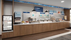 A breakfast station with labeled dispensers for yogurt, eggs, and milk, and sections for fruit, hot food, bakery, and cereal. - Holiday Inn Express Hotel & Suites Chambersburg by IHG (Chambersburg)