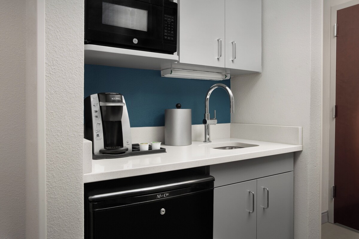 A compact kitchen with a microwave, coffee maker, and a sink.