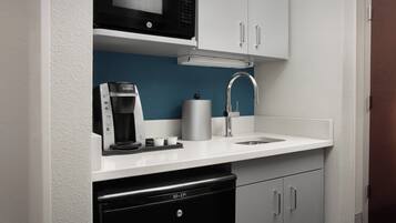 Cocina compacta con microondas, cafetera y lavavajillas.