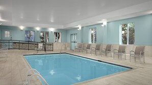 A swimming pool with a tiled deck, a changing room, and a seating area with chairs. - Holiday Inn Express Hotel & Suites Chambersburg by IHG (Chambersburg)