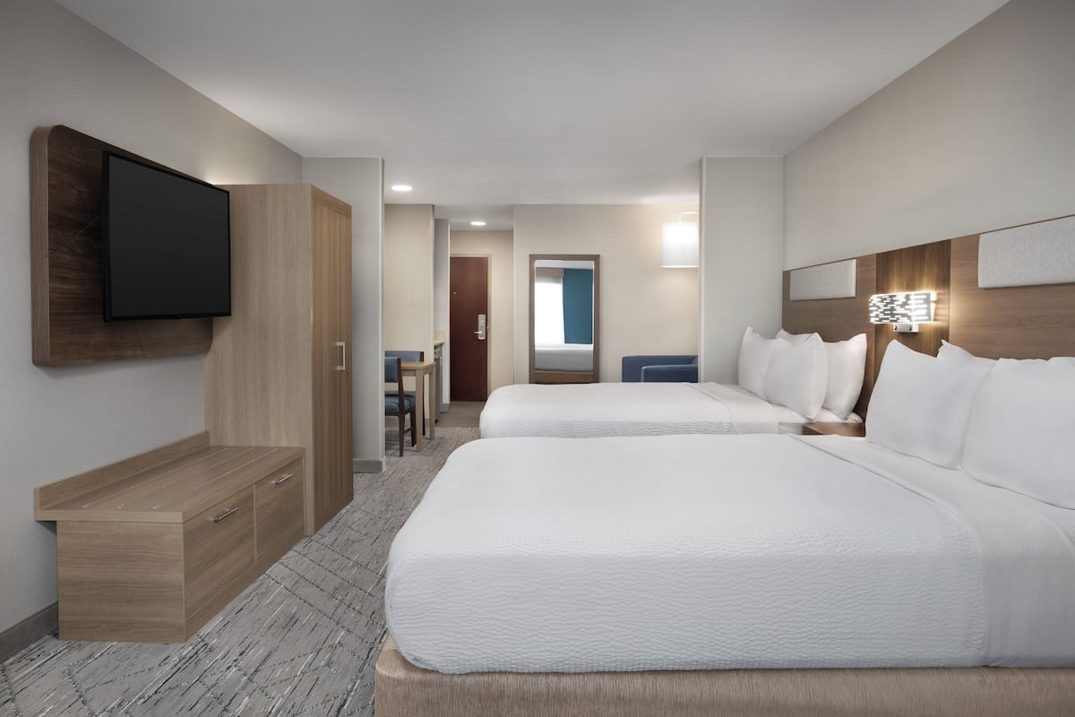 Une chambre d’hôtel avec deux lits, un téléviseur fixé au mur, un bureau et une chaise.