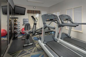 Un centre de remise en forme équipé de tapis de course, de ballons d’exercice et d’un vélo d’appartement.