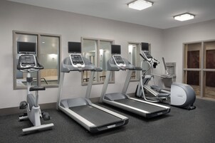 Un gimnasio con cintas de correr, elípticas y una bicicleta estática.