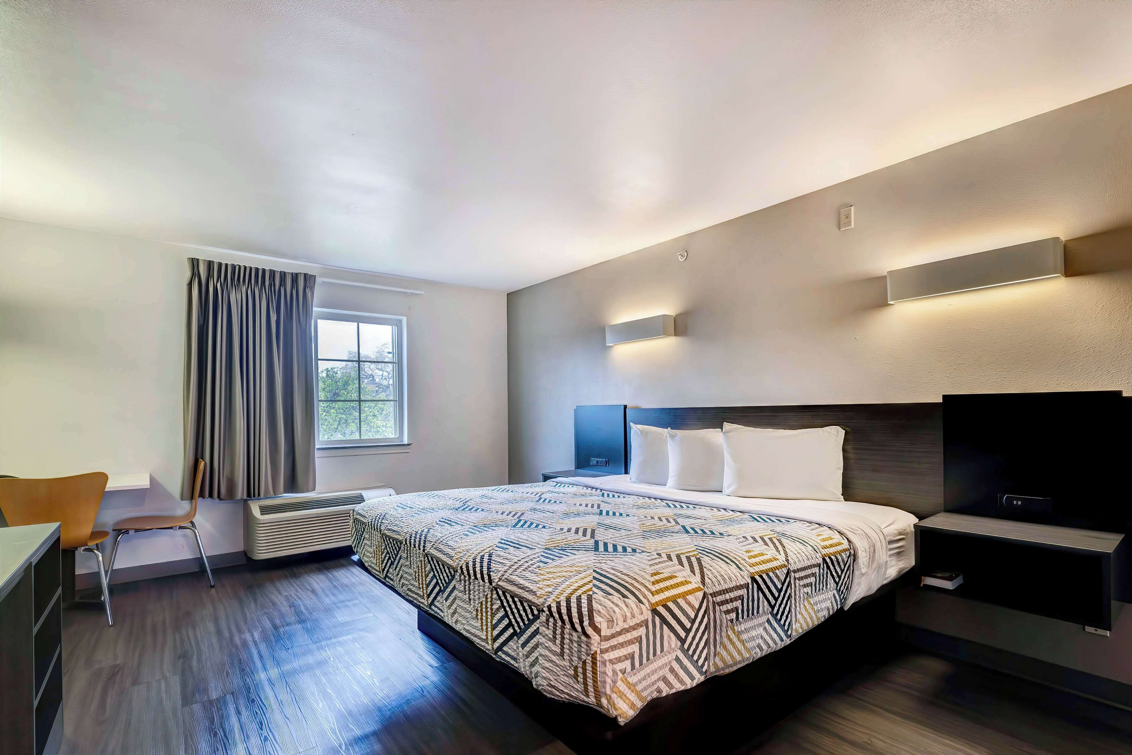 A modern hotel room with a large bed, a desk, and a TV.