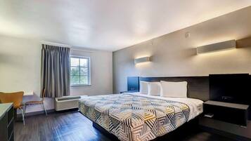 A modern hotel room with a large bed, a desk, and a TV.