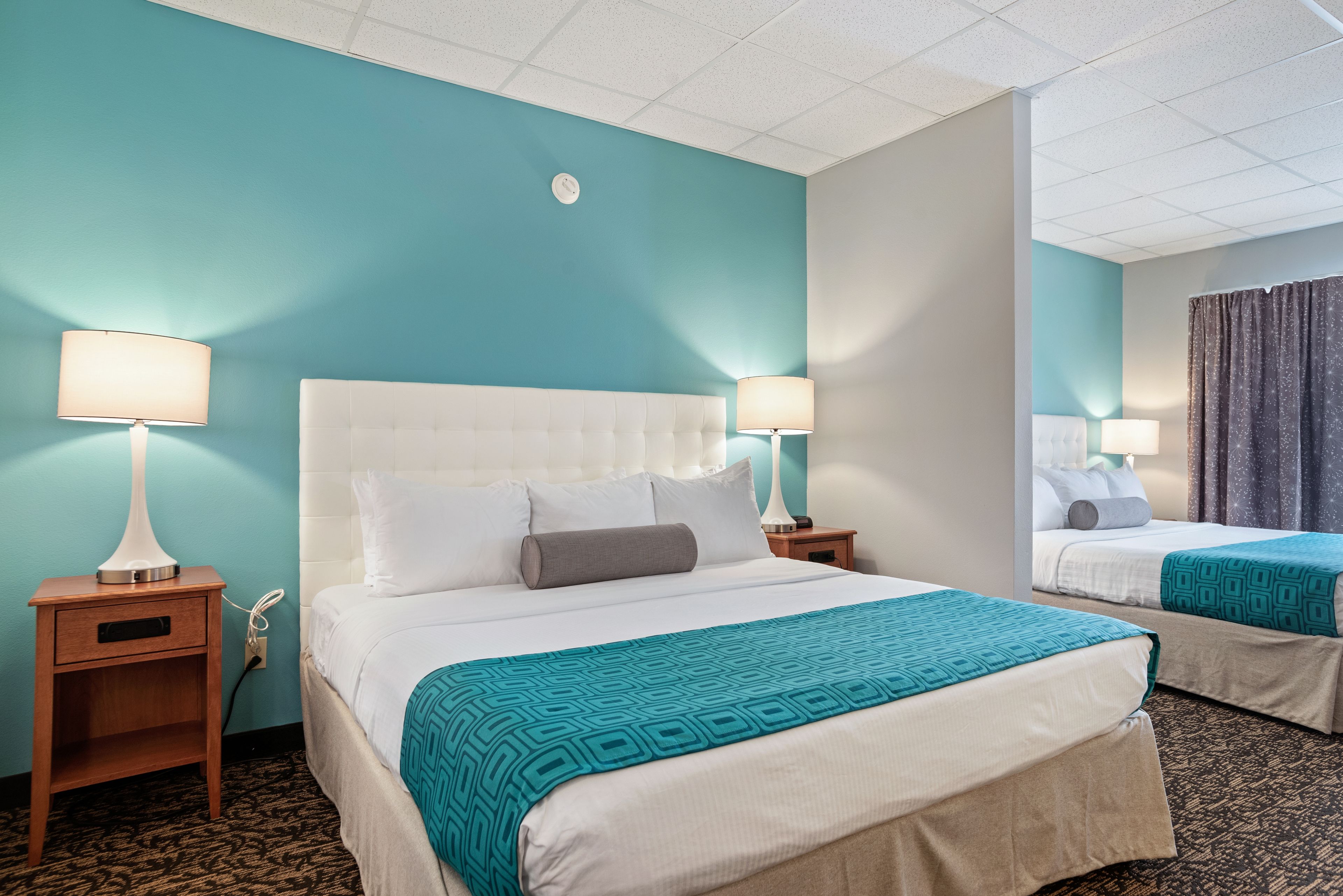 Una habitación de hotel con una cama grande, dos mesitas de noche y un espejo.