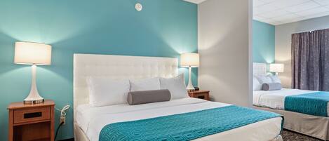 Una habitación de hotel con una cama grande, dos mesitas de noche y un espejo.