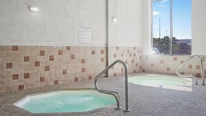 A spa area with two hot tubs, a tiled wall, and a window with a view. - Elevation Inn & Suites, Trademark Collection by Wyndham (Rapid City)