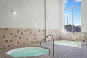 Un espace bien-être comprenant deux bains à remous, un mur carrelé et une fenêtre offrant une vue agréable.
