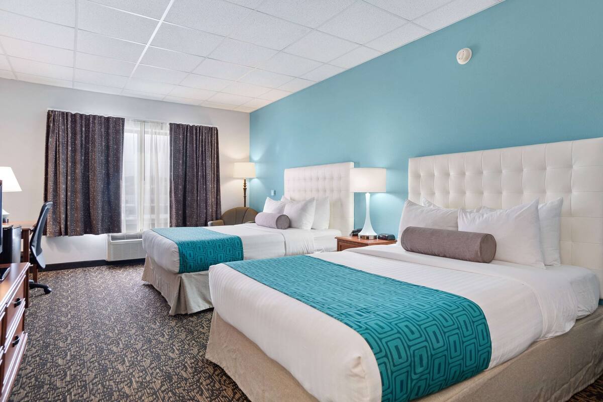 Ein Hotelzimmer mit zwei Betten, einem Schreibtisch und einem Fernseher.