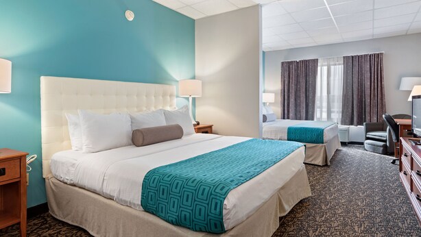 A hotel room with a large bed, a smaller bed, a desk, and a TV. - Elevation Inn & Suites, Trademark Collection by Wyndham (Rapid City)