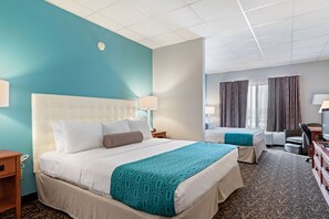 Una habitación de hotel con una cama grande, una cama más pequeña, un escritorio y un televisor.