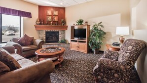 A living room with a fireplace, a television, and comfortable seating. - Elevation Inn & Suites, Trademark Collection by Wyndham (Rapid City)