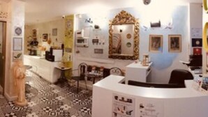 Un vestíbulo de hotel con mostrador de recepción, escalera y alfombra estampada.