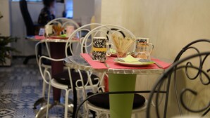 Comedor con mesas dispuestas para comidas, con sillas de metal y un suelo estampado.