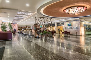 A spacious lobby with a modern design, featuring a central seating area, a bar, and a display wall with photos. - President Hotel (Kyiv)