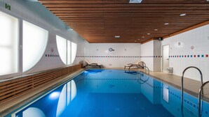 An indoor swimming pool with wooden ceiling panels, clear glass windows, and tiled walls. - President Hotel (Kyiv)