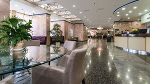 A spacious lobby with a reception desk, seating area, and a glass table. - President Hotel (Kyiv)