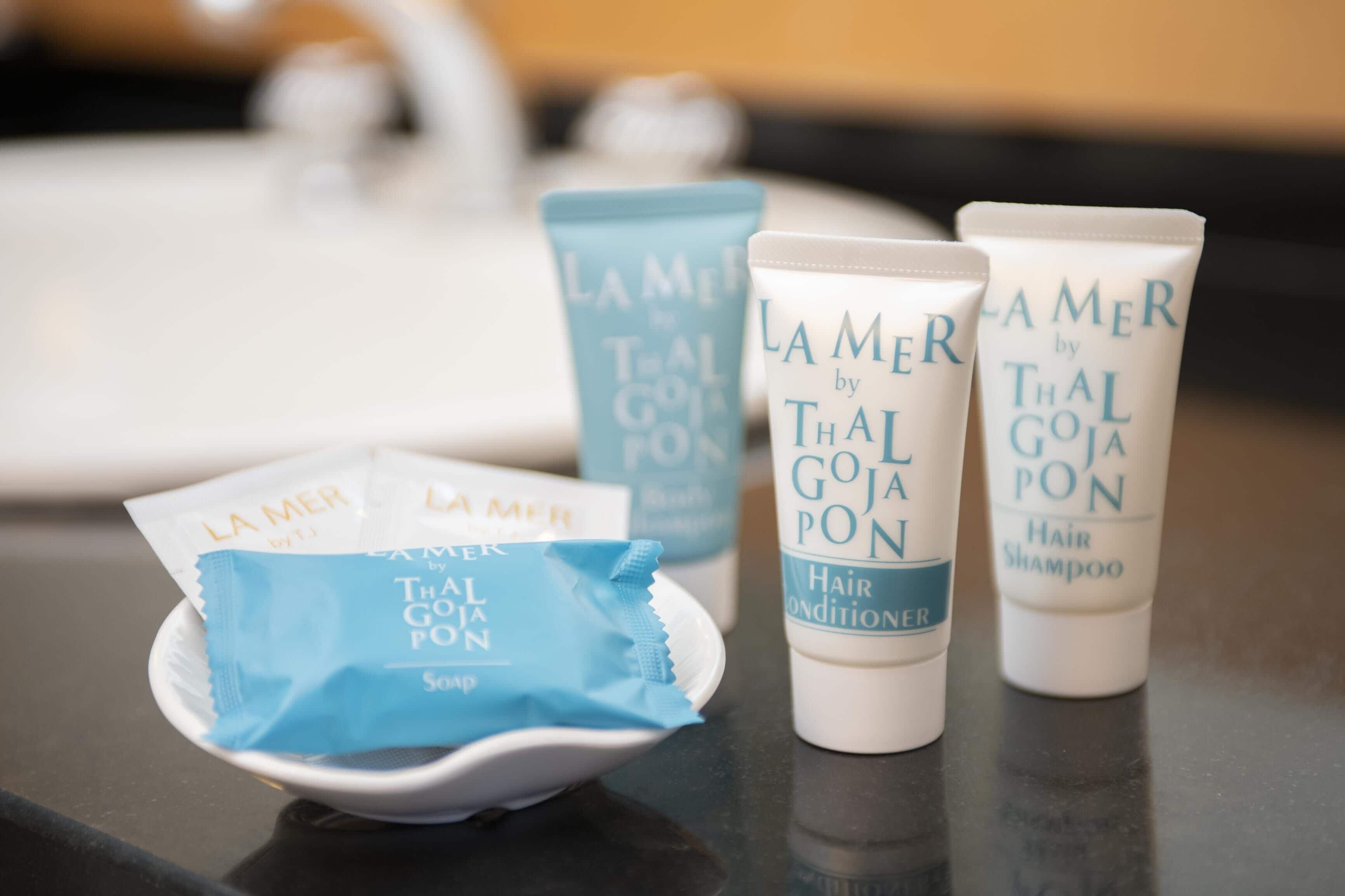 Três produtos para cabelo da La Mer, fotografados por Thal Goja Pon, sobre uma mesa.