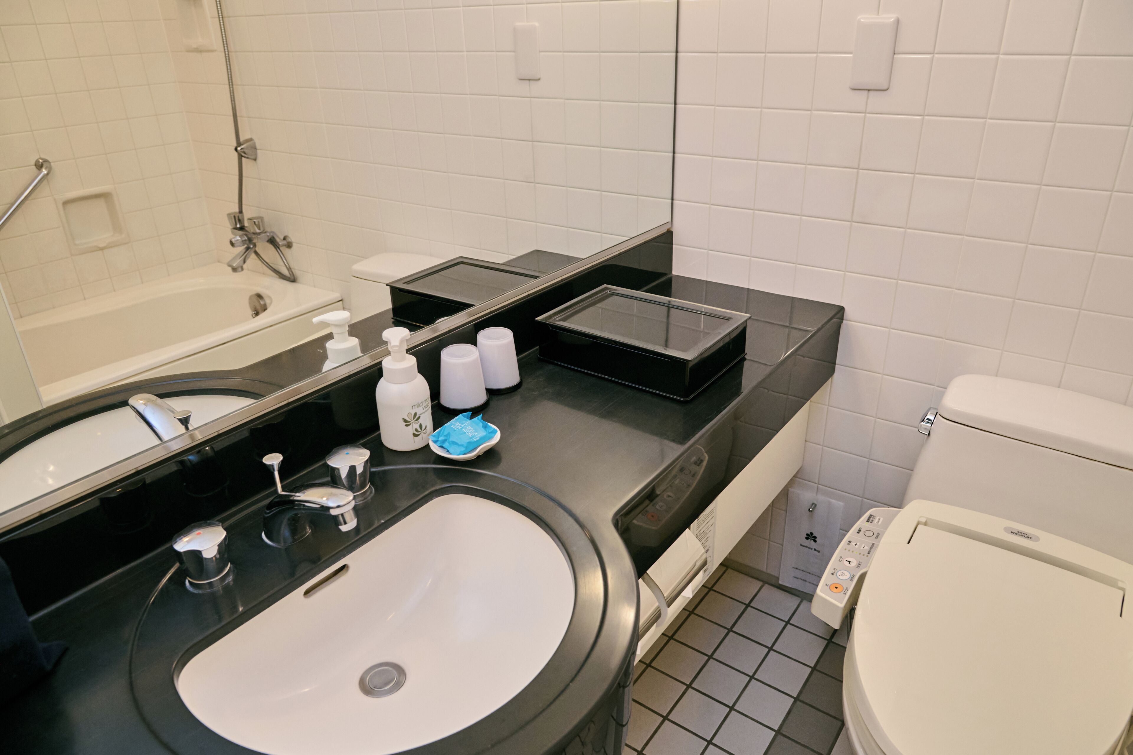 A modern bathroom with a black sink, white toilet, and a glass shower enclosure.
