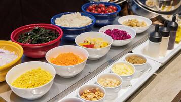 A buffet table with various food items in bowls.
