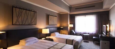 A hotel room with two beds, a desk, a chair, a TV, and a window with curtains.