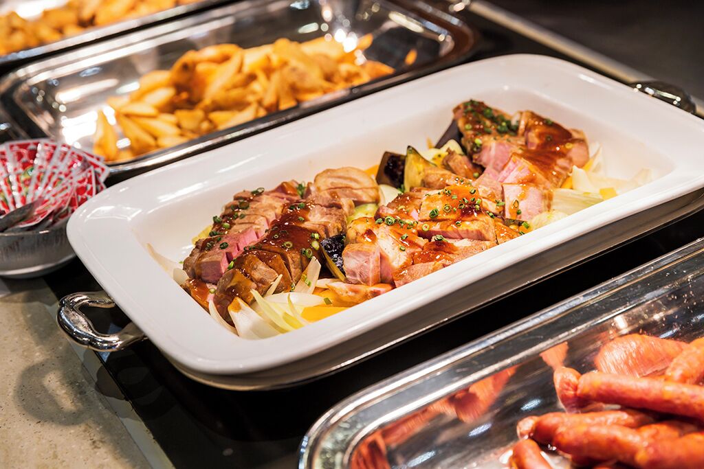 A buffet with various dishes including sliced meat and potatoes.