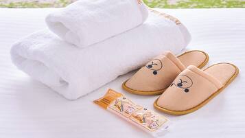 Ein ordentlich gefaltetes weißes Handtuch, ein Paar beige Slippers mit einem niedlichen Gesichtsmotiv und eine kleine Creme-Packung.
