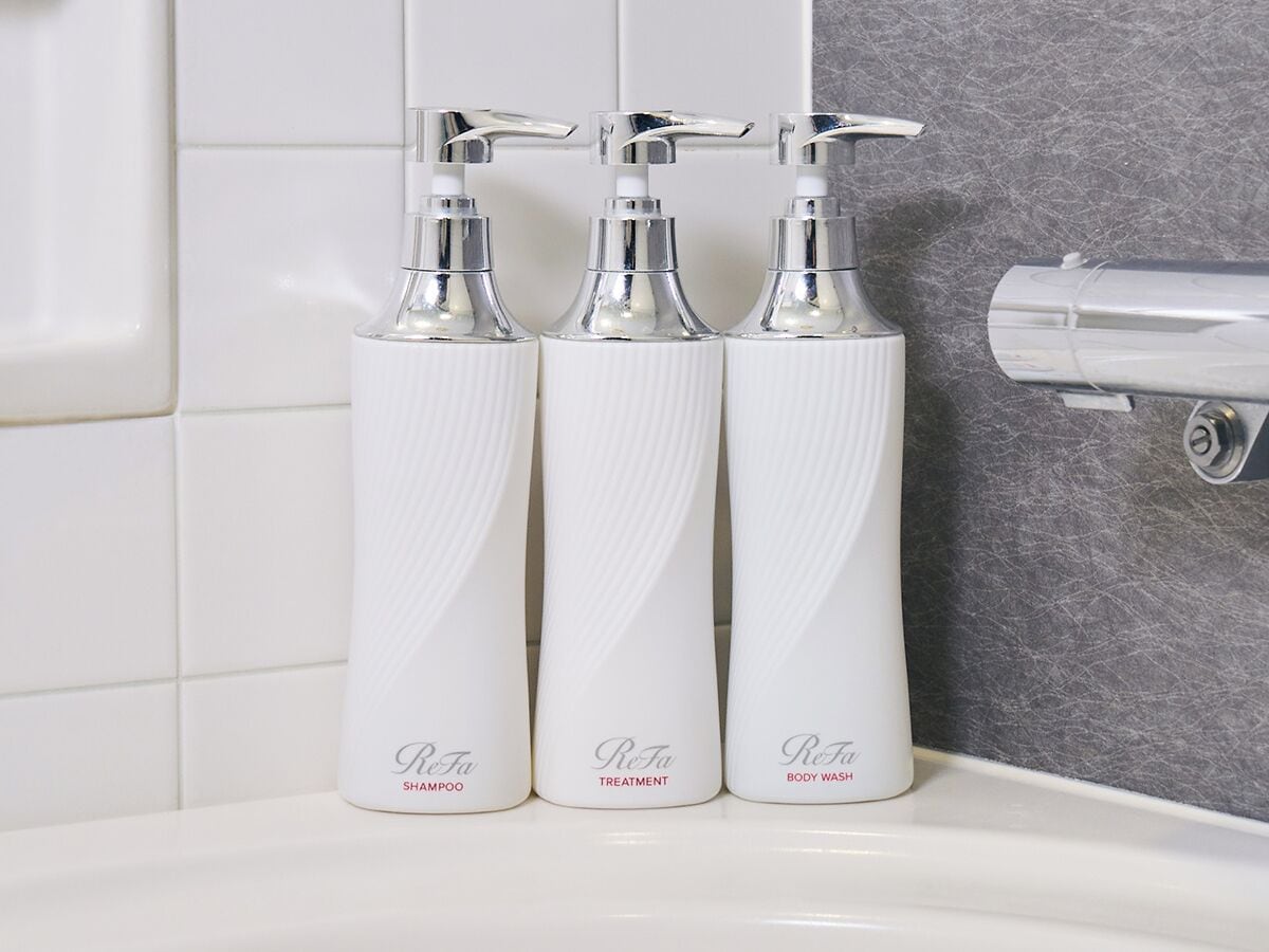 Tres botellas blancas con dosificadores sobre un lavabo de baño.
