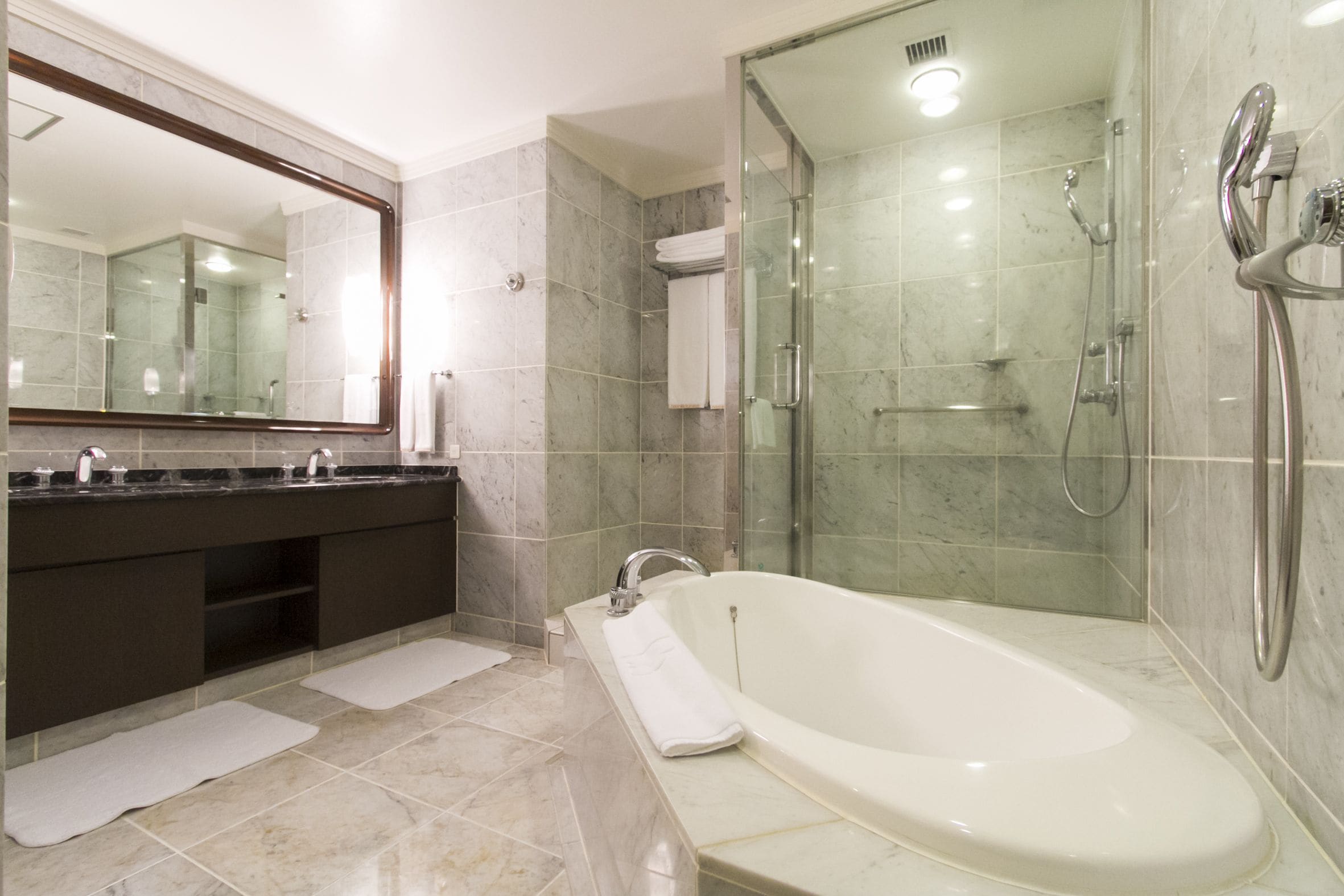 A modern bathroom with a bathtub, a glass-enclosed shower, and a large mirror.