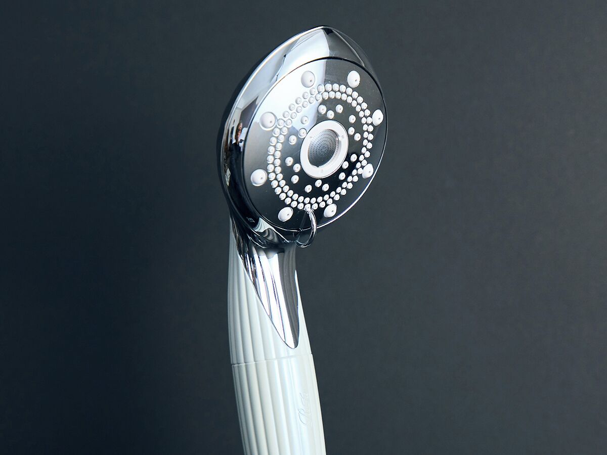 A chrome shower head with a circular design and a white handle.