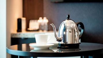 A stainless steel coffee pot and a white cup on a round table.