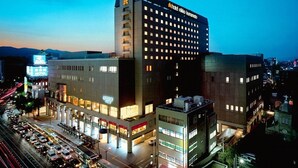 A multi-story hotel with a prominent 'Hotel Nikko Kumanoto' sign, featuring a modern architectural design with a flat roof and a mix of glass and concrete facades. - Hotel Nikko Kumamoto (Kumamoto)