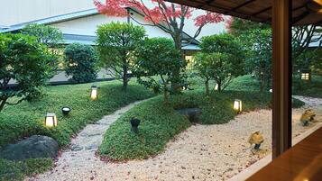 A garden pathway with lanterns, rocks, and trees.