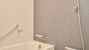 A bathroom with a white bathtub, a shower with a glass door, and a grab bar.