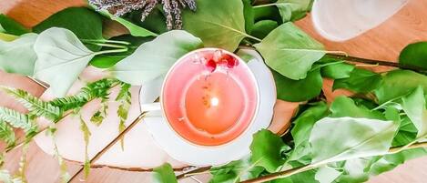 Una mesa con una vela, un vaso de agua y hojas verdes.