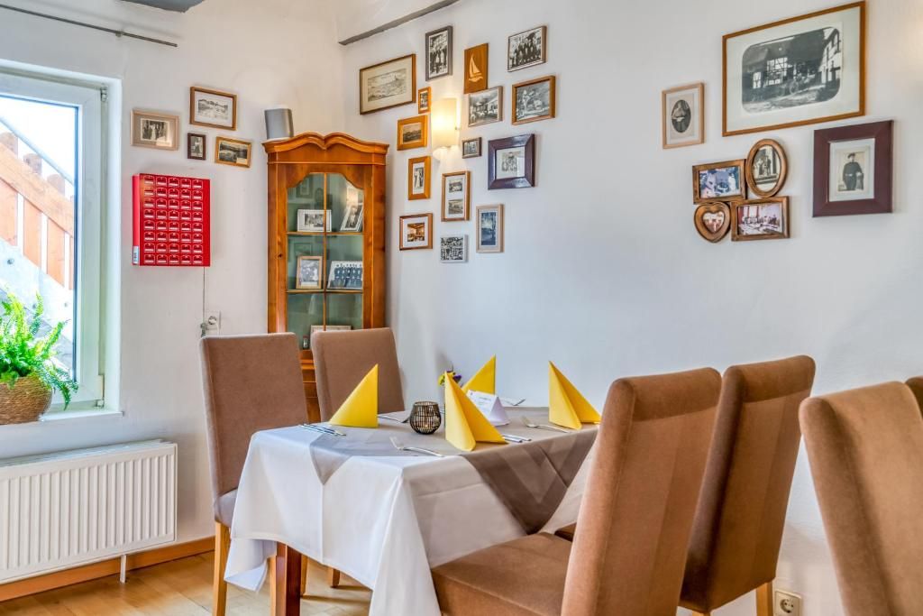 A dining area with a table set for four, chairs, and a wall adorned with framed pictures.