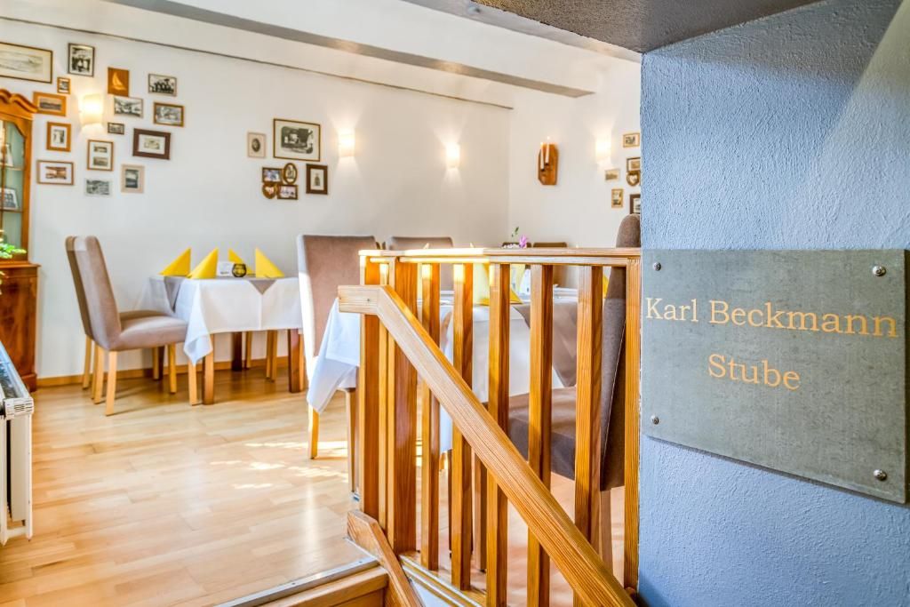 Habitación de hotel con una escalera de madera, zona de comedor con mesa y sillas, y una pared decorada con cuadros.