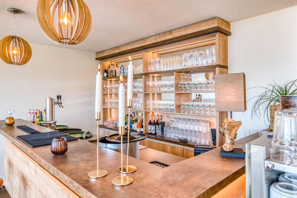 Eine Bar mit einer Holztresen, Regalen für Gläser und Flaschen sowie Pendelleuchten.