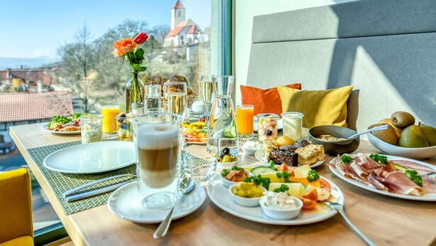 A breakfast table with various dishes, glasses, and a vase of flowers. - Hotel Beckmann (Goettingen)