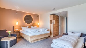 A modern hotel room with a large bed, a smaller bed, a desk, and a chair. - Hotel Beckmann (Goettingen)